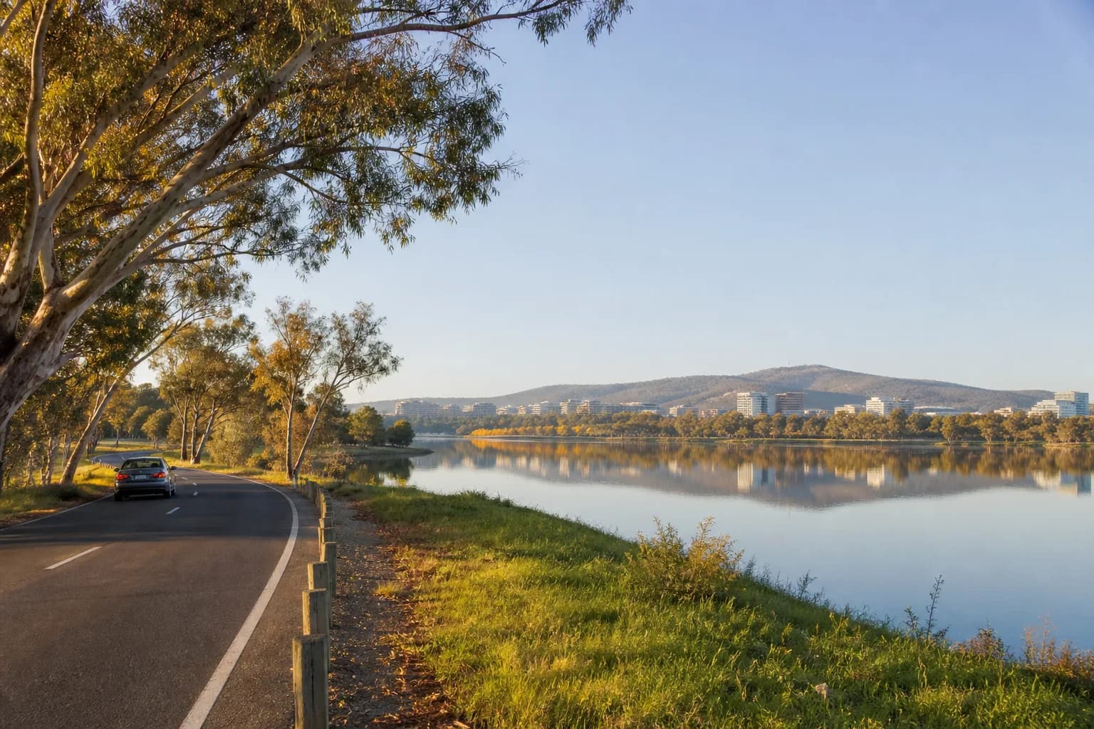 A rental car beside Lake Burley Griffin with Canberra and its hills beyond