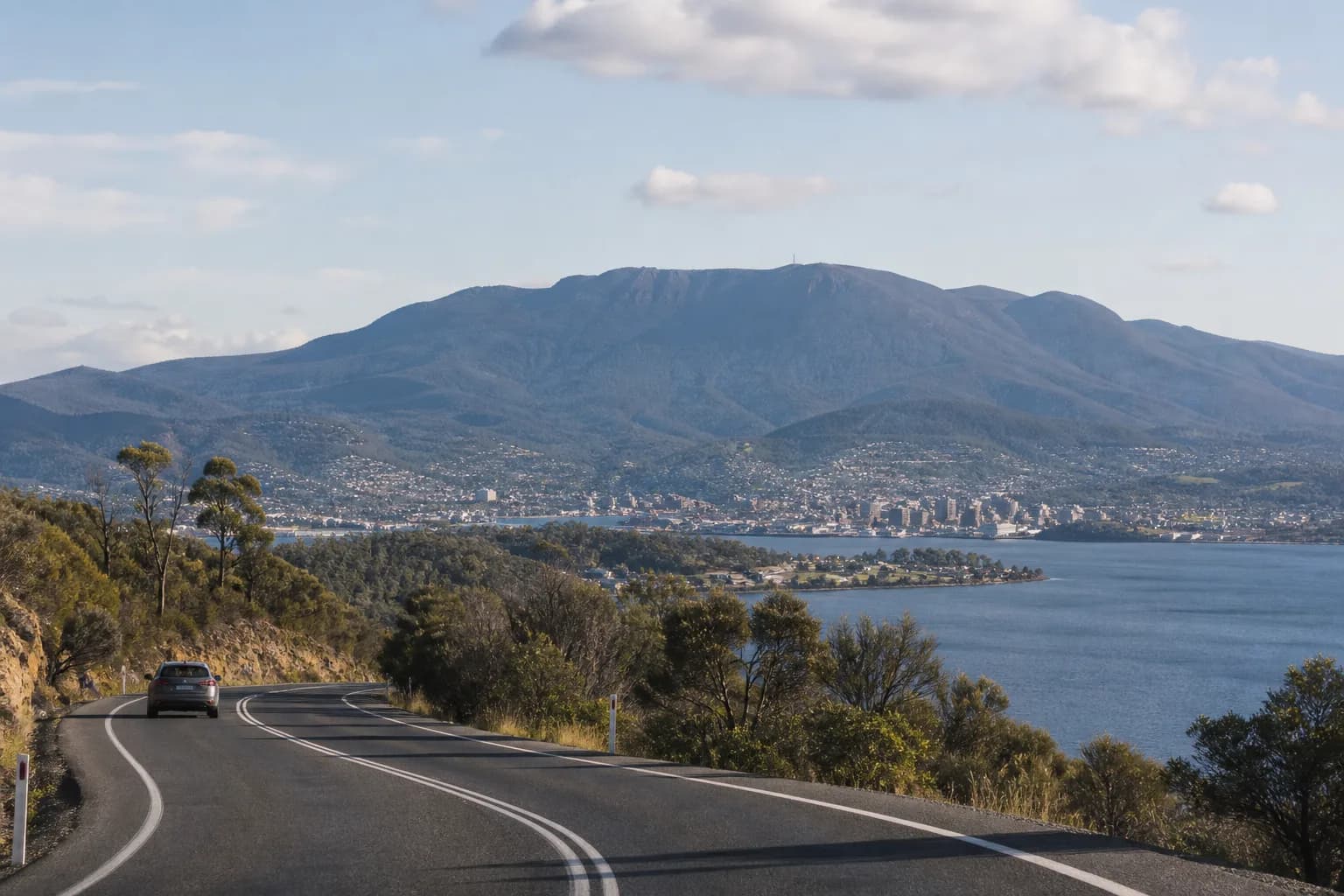 A rental car on a scenic road overlooking Hobart, the Derwent River and the mountain