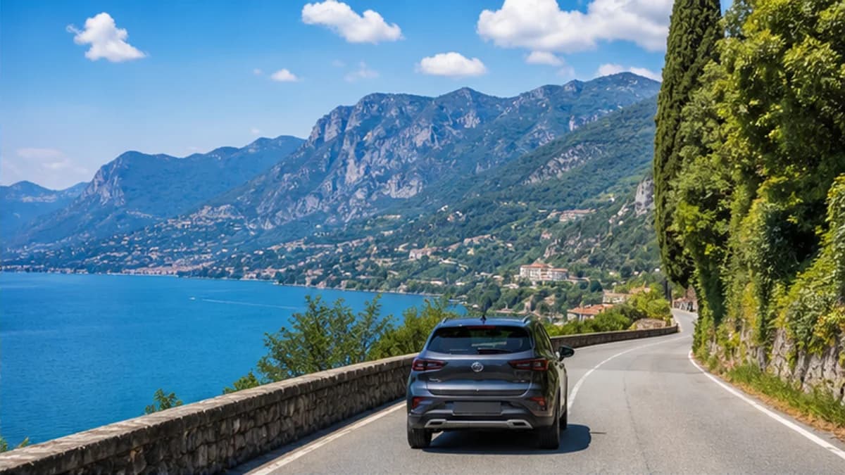Rental car on a lakeside road beneath the Alps near Bergamo