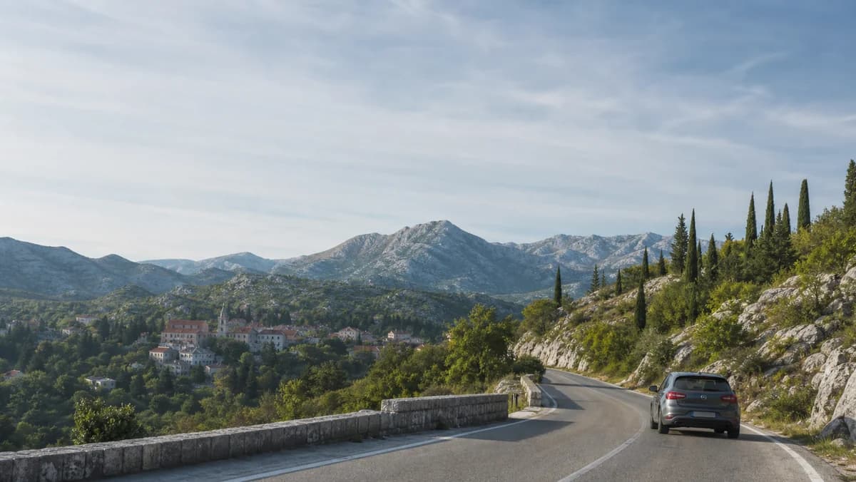 Rental car on a mountain road above Cetinje, Montenegro, with wooded Lovćen hills