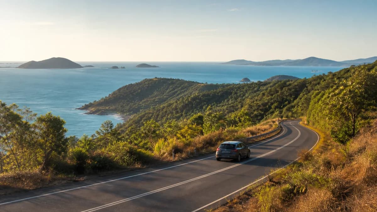 Rental car on a tropical Whitsunday coastal road near Airlie Beach