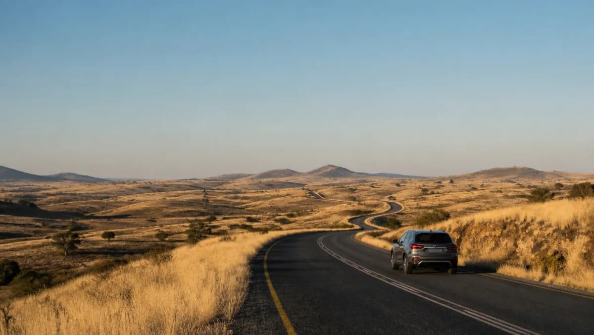 Rental car on an open road through Namibia's dry highland landscape